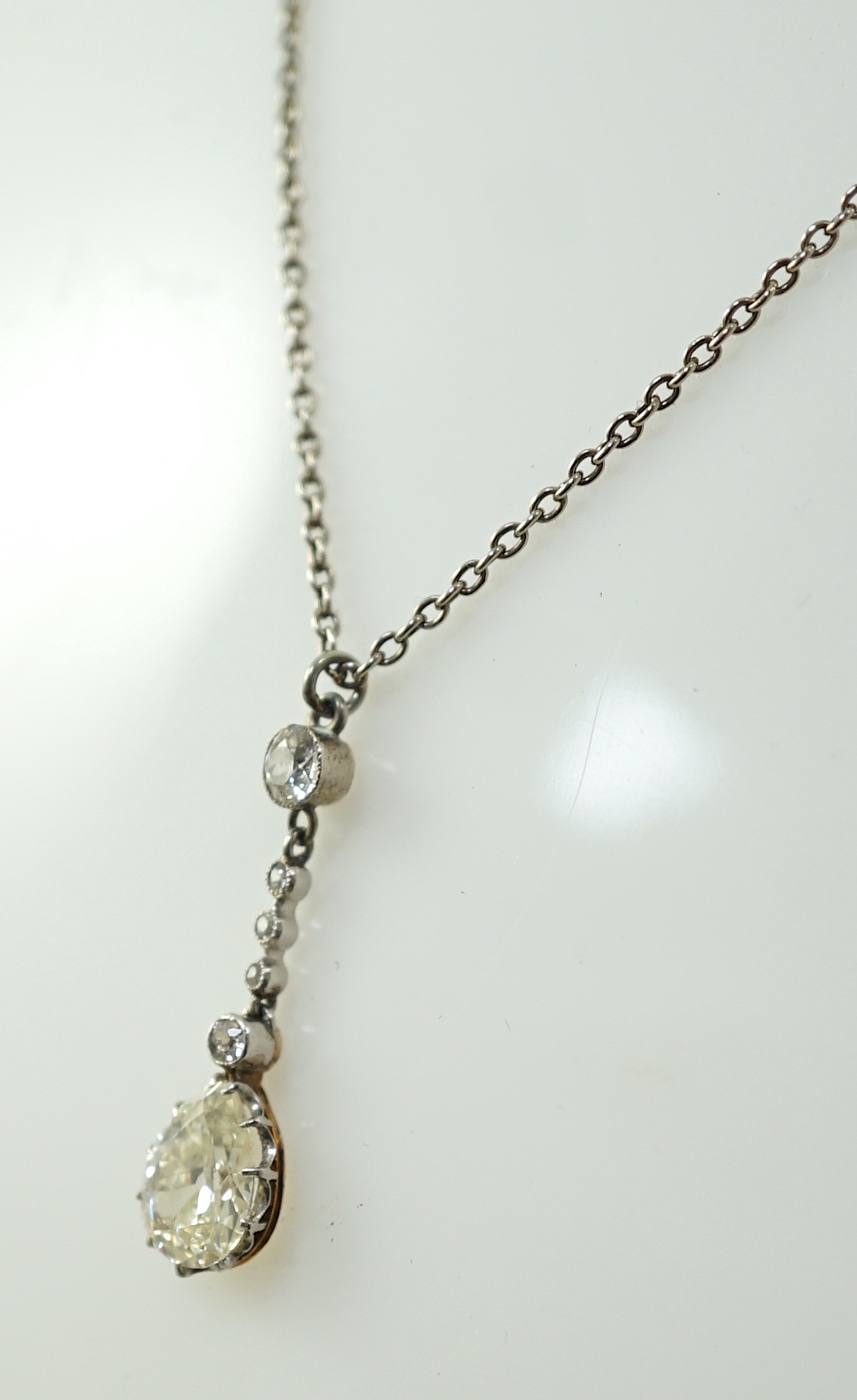 An early to mid 20th century white and yellow gold, six stone diamond set drop pendant, on a white gold chain, the clasp stamped 9k